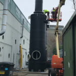 Two black chemical storage tank being installed using a scissor lift
