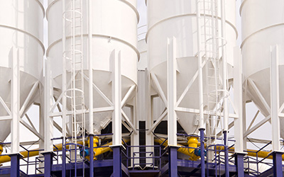 Four white tanks next to each other outside with blue ladders underneath