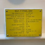 Yellow bulk storage tank sign with specifications on it