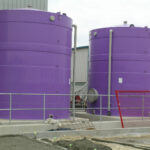 Two purple tanks next to each other outside a warehouse