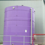 Purple tank next to a warehouse with grey pipe on the right and red fencing at the bottom right
