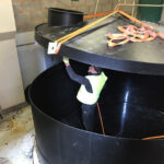 Man in high viz inside the tank lifting up the lid